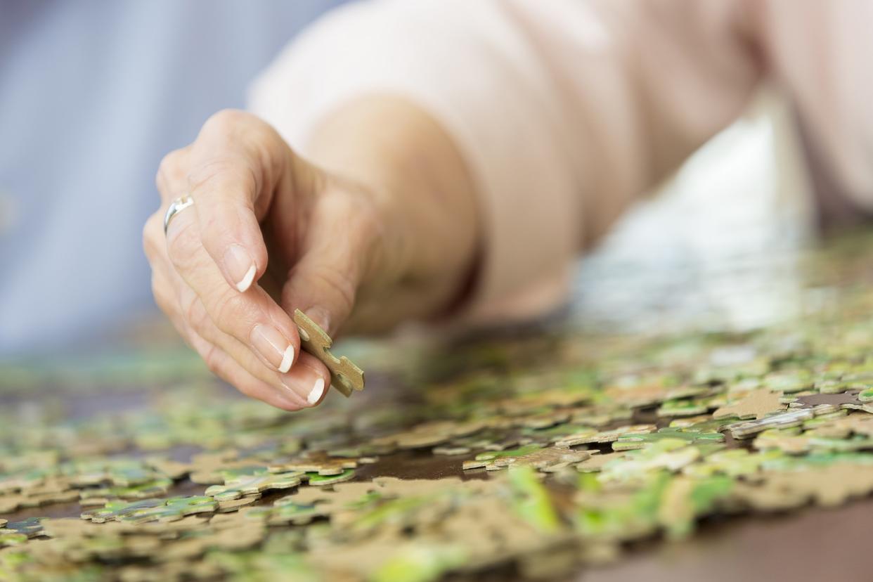 close up of senior woman's hand putting together puzzle