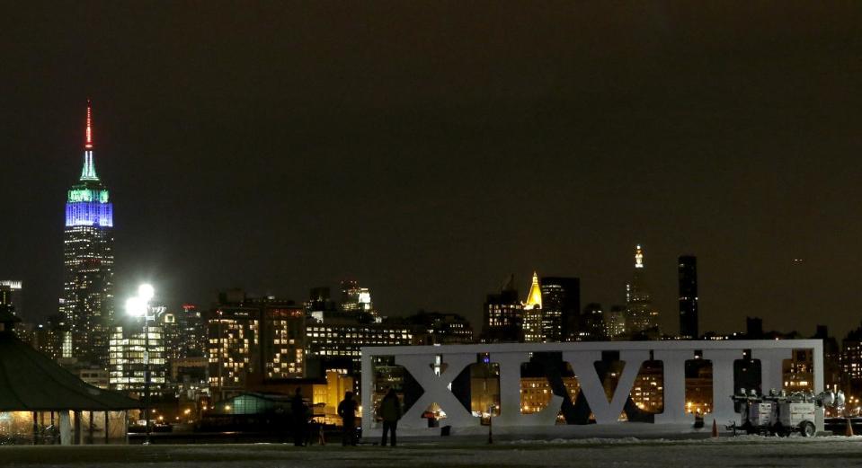 People watch fireworks as they stand near the Roman numerals for NFL Super Bowl XLVIII football game at Pier A Park in Hoboken, N.J., Monday, Jan. 27, 2014. The Seattle Seahawks and the Denver Broncos are scheduled to play in the Super Bowl on Sunday, Feb. 2 at MetLife Stadium in East Rutherford, N.J. The fireworks were part of a kick off event for the game. (AP Photo/Julio Cortez)