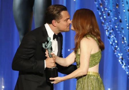 Leonardo Dicaprio greets presenter Julianne Moore as he accepts the award for Outstanding Performance by a Male Actor in a Leading Role for his role in "The Revenant" at the 22nd Screen Actors Guild Awards in Los Angeles, California January 30, 2016. REUTERS/Lucy Nicholson