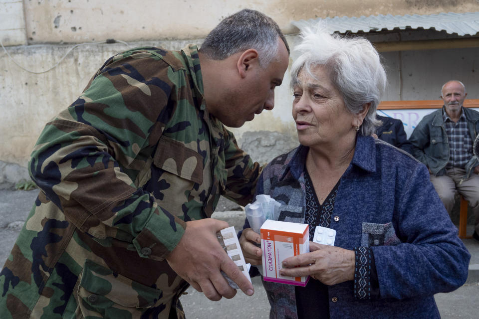 Doctor Aram Gregorian gives drugs to a woman near her apartment building during a military conflict in Stepanakert, the separatist region of Nagorno-Karabakh, Friday, Oct. 16, 2020. As Nagorno-Karabakh's medical system faced a massive challenge, volunteers joined the fight against the virus, delivering medicines to the people hiding in basements and helping track down those infected. (AP Photo)