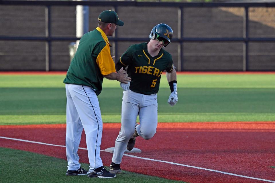 St. Xavier's Jacob Bennett (5) is congratulated by his coach after hitting a 2 run home run during action of their Seventh Region Championship baseball game against Trinity, Sunday, May 29 2022 in Louisville Ky. St. Xavier won 11-0 after he game was called at the end of the fifth inning, and will now play for the state championship.