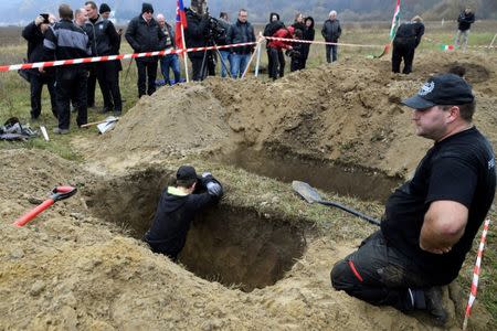 Gravediggers rest after competing in a grave digging championship in Trencin, Slovakia, November 10, 2016, where eleven pairs of gravediggers are competing in digging based on accuracy, speed, and aesthetic quality. REUTERS/Radovan Stoklasa