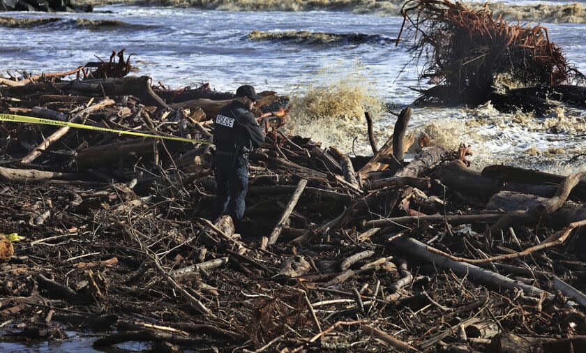 A Capitola police officer tapes off dangerous areas of driftwood along Capitola Beach as strong waves continue to batter the central California coast in Capitola, Calif., Tuesday, Jan. 10, 2023. (Shmuel Thaler/The Santa Cruz Sentinel via AP)