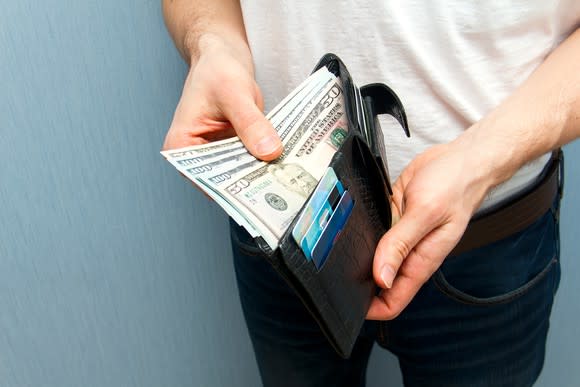 Man opening his wallet and pulling out money.