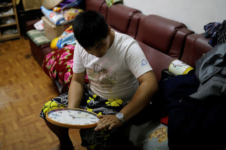 Chen Hong-zhi, 26, who suffers from short-term memory loss, adjusts clock hands at his home in Hsinchu, Taiwan, July 2, 2018. REUTERS/Tyrone Siu