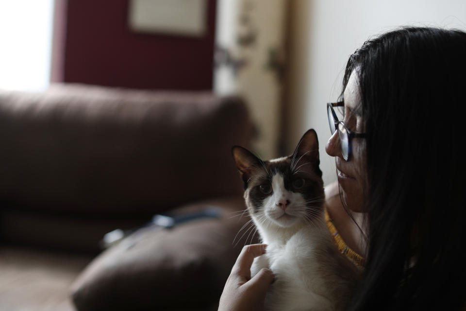 Ximena Canejo Hernandez holds one of the household's two cats as she waits for a few close relatives to arrive to mark her 15th birthday at home, in Tlalnepantla, just outside Mexico City, Monday, July 13, 2020. Ximena's family, wanting to give her a traditional Quinceanera, had booked a church and event hall for July 18th long before the coronavirus pandemic hit, but the celebration had to be postponed until late November. (AP Photo/Rebecca Blackwell)