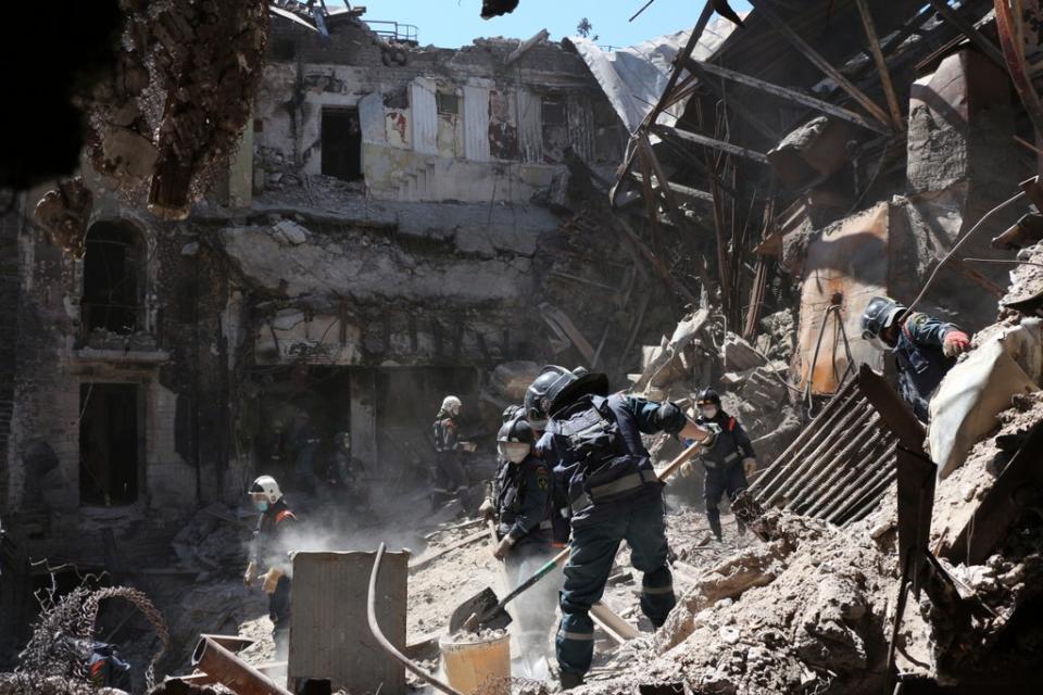 Donetsk People Republic Emergency Situations Ministry employees clear rubble at the side of the damaged Mariupol theatre on May 12 (AP)