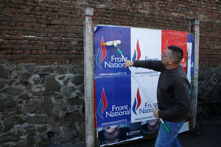 Emmanuel Rignaux, a member of the National Front party, pastes a poster on a free billboard for French far right National Front political party leader Marine Le Pen as part of the 2017 French presidential election campaign in Henin-Beaumont, France, April 6, 2017. REUTERS/Pascal Rossignol