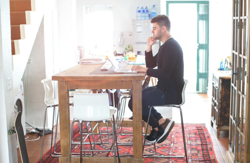 Man sitting at a table  at home and working on a laptop