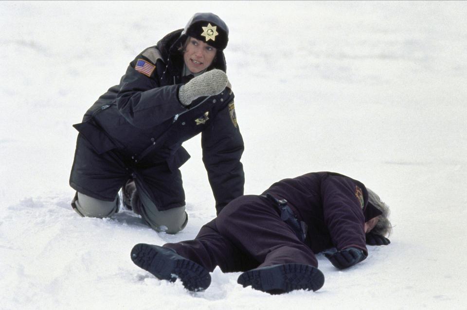 A female police officer investigates a dead body lying in the snow