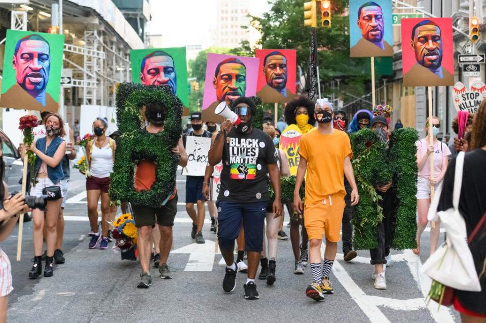 Marchers with placards depicting a man's face in a protest for racial justice