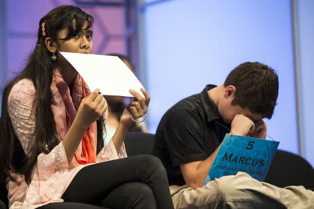 Eesha Sohail (L) of Bakersfield, California, bites her name placard while Marcus Behling of Scottsdale, Arizona, rubs his eyes during the semi-final round of the 88th annual Scripps National Spelling Bee at National Harbor, Maryland May 28, 2015. REUTERS/Joshua Roberts