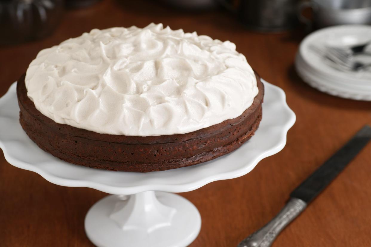 A flourless chocolate cake sits on a cake stand, ready for consumption.