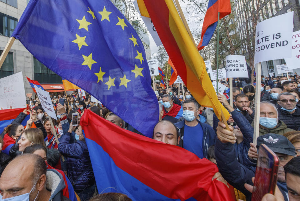 Protestors wave EU flags and hold signs outside of an EU summit meeting in Brussels to demonstrate in support of Armenia and against the war in the Nagorno-Karabakh region, Thursday, Oct. 1, 2020. The mountainous region of Nagorno-Karabakh, where deadly new fighting has erupted in recent days between Armenian and Azerbaijani military forces, has been in a tense limbo since a 1994 truce. (AP Photo/Olivier Matthys)