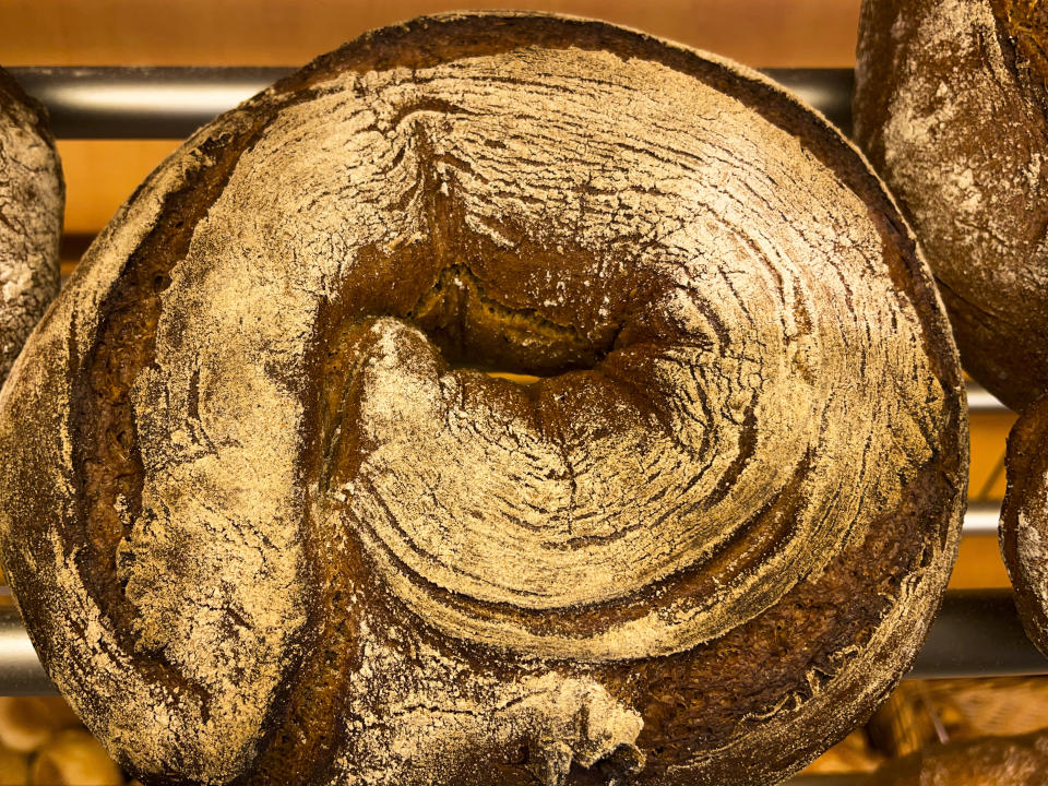 A bread loaf that was baked with beer is displayed in the Coelven bakery in Duesseldorf, Germany, Tuesday, March 23, 2021. About 6,000 litres of the renowned copper-colored 'Altbier' of the historic Fuechschen brewery remain unsold and nearing its expiry date. The brewery now works with craft bakers who use the beer to make bread, with about twelve bakeries producing the grain bread and are giving the additional bonus of a bottle of Fuechschen's Altbier free of charge with every loaf.(AP Photo/Daniel Niemann)