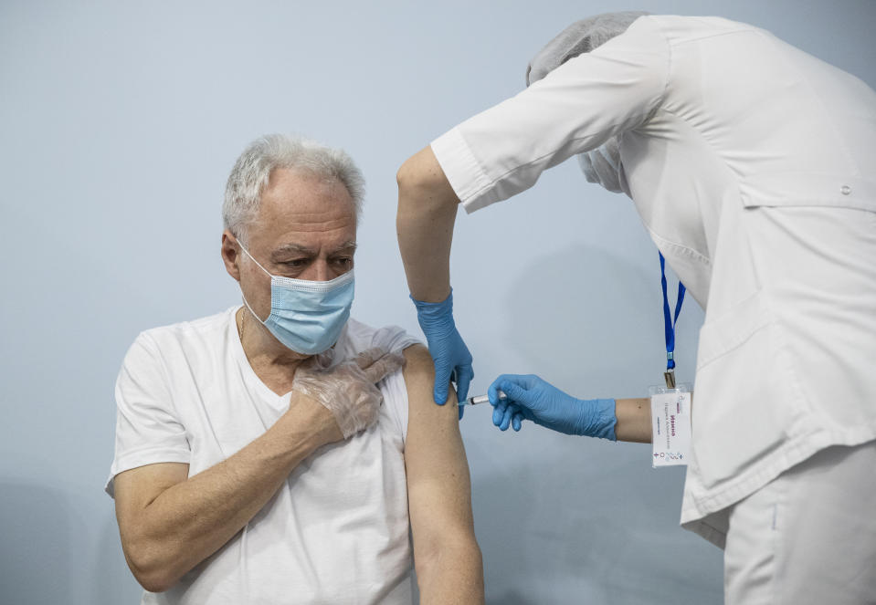 A Russian medical worker, right, administers a shot of Russia's Sputnik V coronavirus vaccine to a patient in a vaccination center in Moscow, Russia, Wednesday, Jan. 20, 2021. Russia started a mass coronavirus vaccination campaign on Monday, Jan. 18. (AP Photo/Pavel Golovkin)