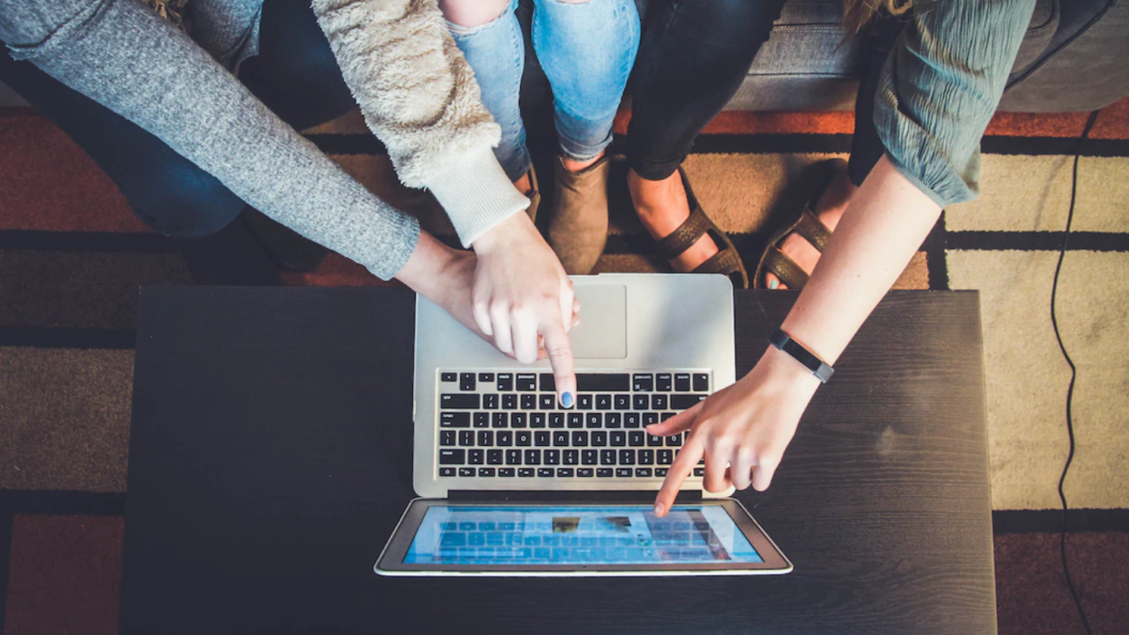  Three people gathered around a laptop 