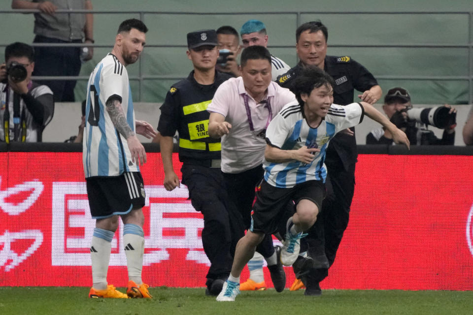 Argentina's Lionel Messi, left, watches as security officers pursue a fan during play on the field in their friendly soccer match at Workers' Stadium in Beijing, Thursday, June 15, 2023. (AP Photo/Mark Schiefelbein)