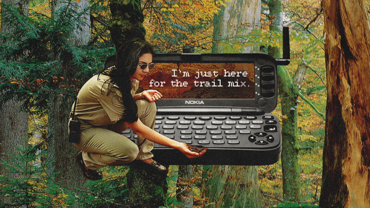 a man sitting on a chair with a laptop in the woods