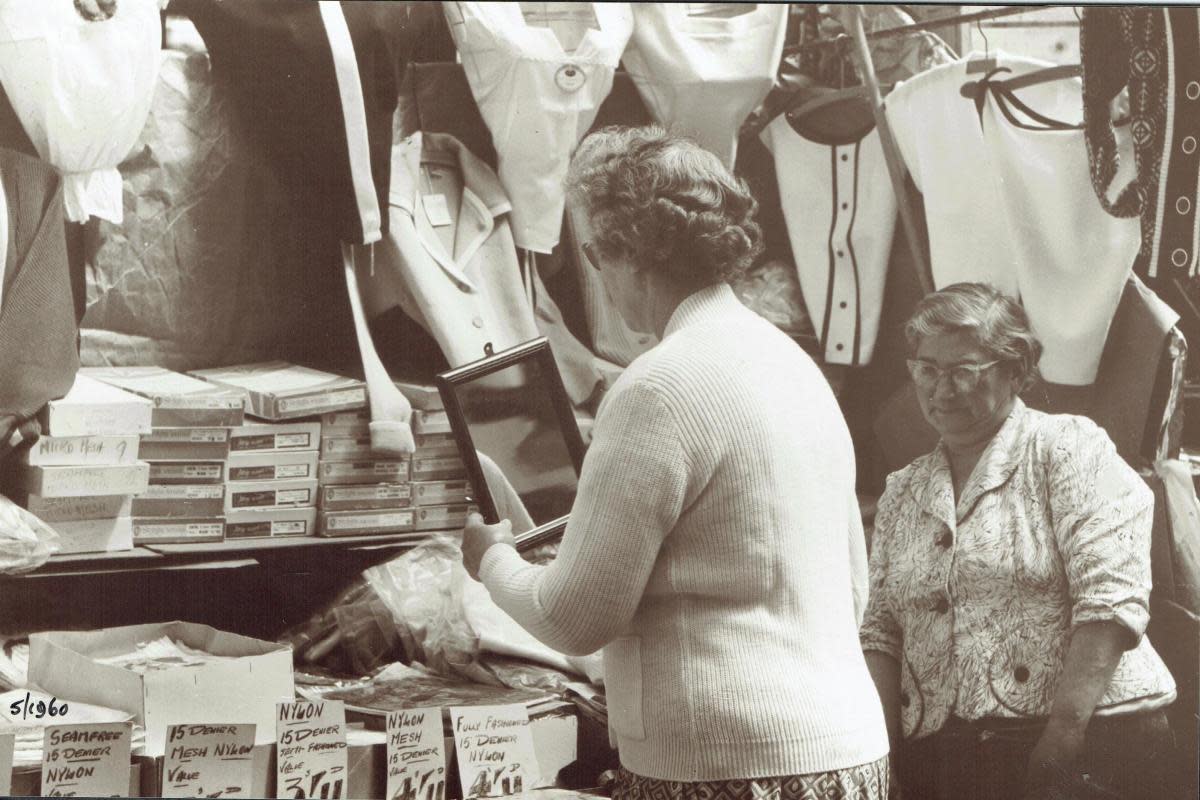 The customer checks the fit of the cardigan in the mirror. Image: Bob Nunn/Watford Museum