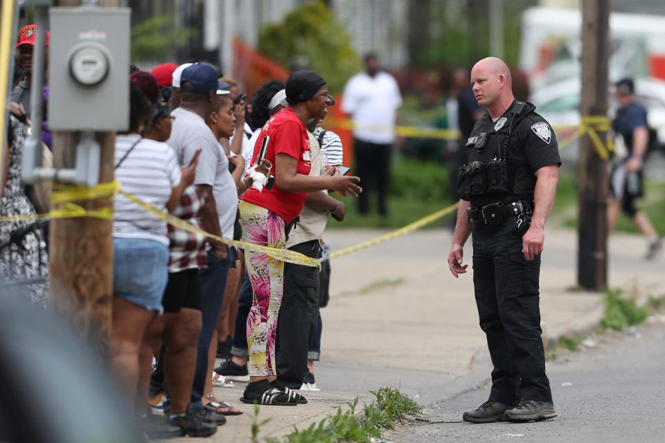 Police speak to bystanders while investigating after a shooting at a supermarket Saturday in Buffalo, N.Y. Officials said the gunman entered the supermarket with a rifle and opened fire.