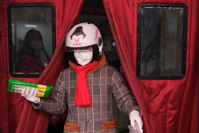 A woman wearing a face mask walks out of a supermarket, as the country is hit by an outbreak of the new coronavirus, in Beijing