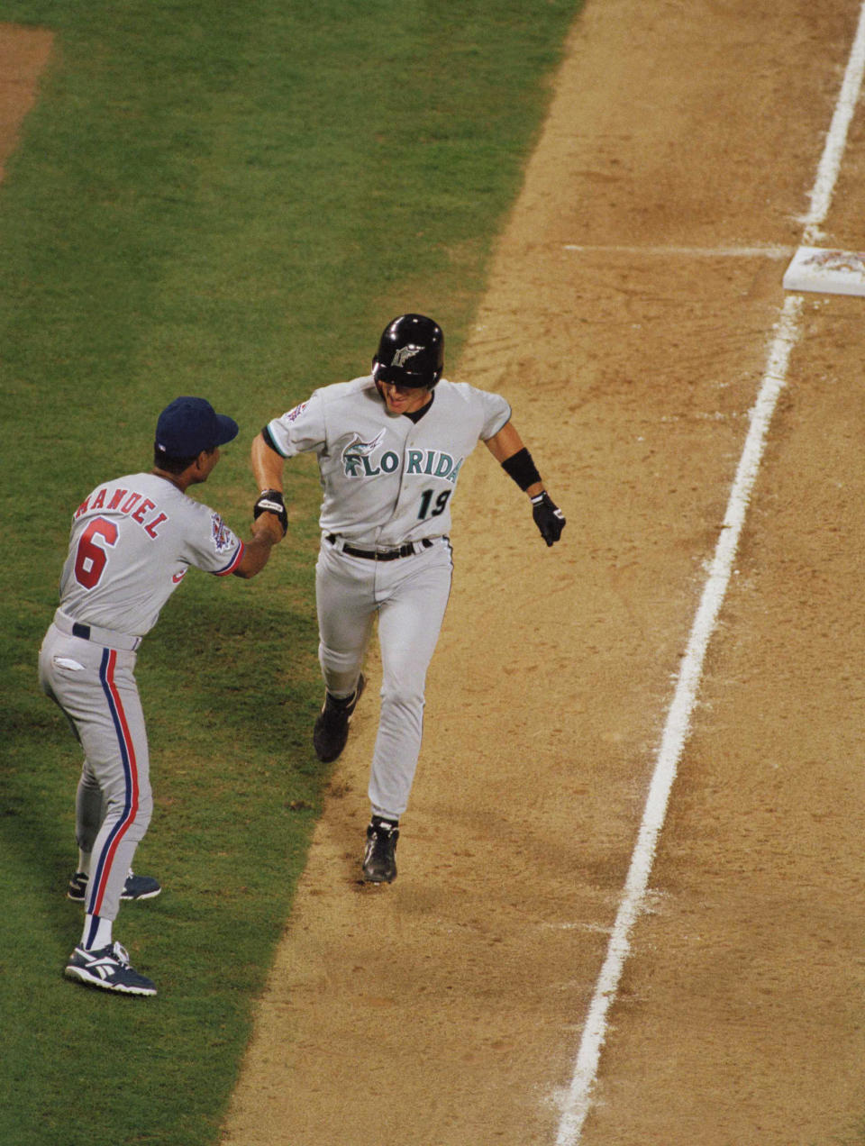 FILE - Florida Marlins' Jeff Conine, right, is congratulated by third base coach Jerry Manuel, of the Montreal Expos, after hitting the winning home run in the eighth inning of the All-Star baseball game in Arlington, Texas, July 11, 1995. Major League Baseball is playing its All-Star Game in Arlington for the first time since 1995, when the Rangers played outside in the stifling heat. This year's game will be played Tuesday, July 16, 2024, in their stadium with a retractable roof that opened in 2020. (AP Photo/Pat Sullivan, File)