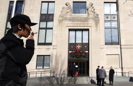 A cigarette smoker stands in the designated smoking area across the street from the National Headquarters of the American Red Cross in Washington, December 30, 2014. REUTERS/Larry Downing