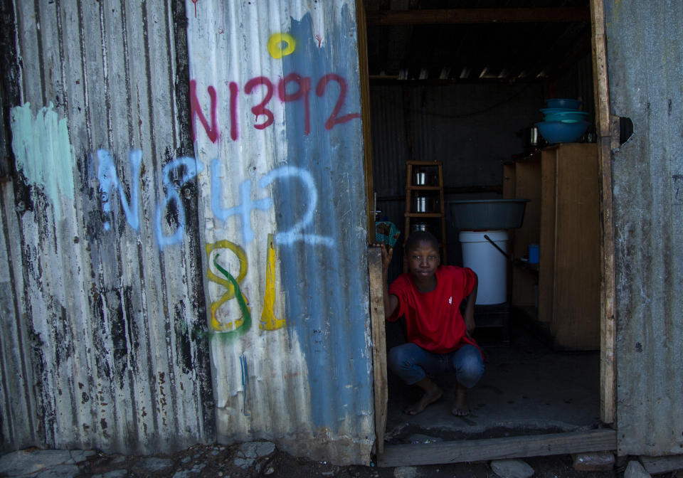In this photograph taken Thursday March 19, 2020, a woman sits at the entrance of her home in a squatter camp in Soweto, South Africa. Some countries around the world lack the equipment and trained health workers to respond to the threat of COVID-19 virus. For most people the virus causes mild or moderate symptoms, but for others it causes severe illness. (AP Photo/Themba Hadebe)
