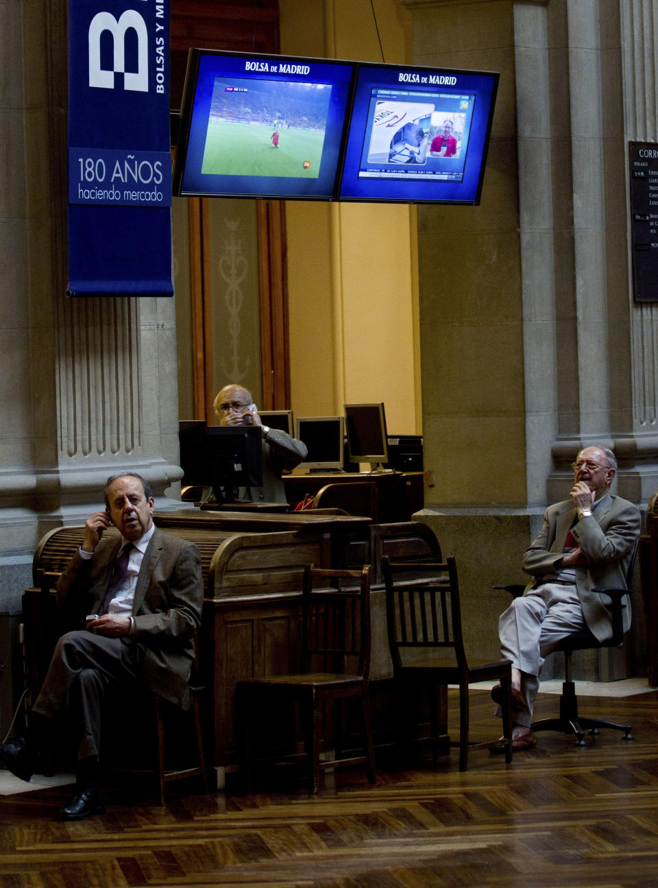 Brokers work as an image of the Euro 2012 soccer tournament appears on a screen at the Stock Exchange in Madrid Monday June 18, 2012. Spanish markets breathed a sigh of relief Monday with stocks opening higher and the country's borrowing costs dipping slightly after pro-bailout parties won the elections in Greece. Spain is a focus of fears it might be the next eurozone country to need a full bailout. The government is to announce this week how much of a euro100 billion fund it will tap to rescue banks that got burned when a real estate bubble popped. (AP Photo/Paul White)