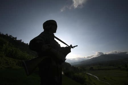 An Indian army soldier stands guard while patrolling near the Line of Control, a ceasefire line dividing Kashmir between India and Pakistan, in Poonch district August 7, 2013 in this file photo. REUTERS/Mukesh Gupta/Files