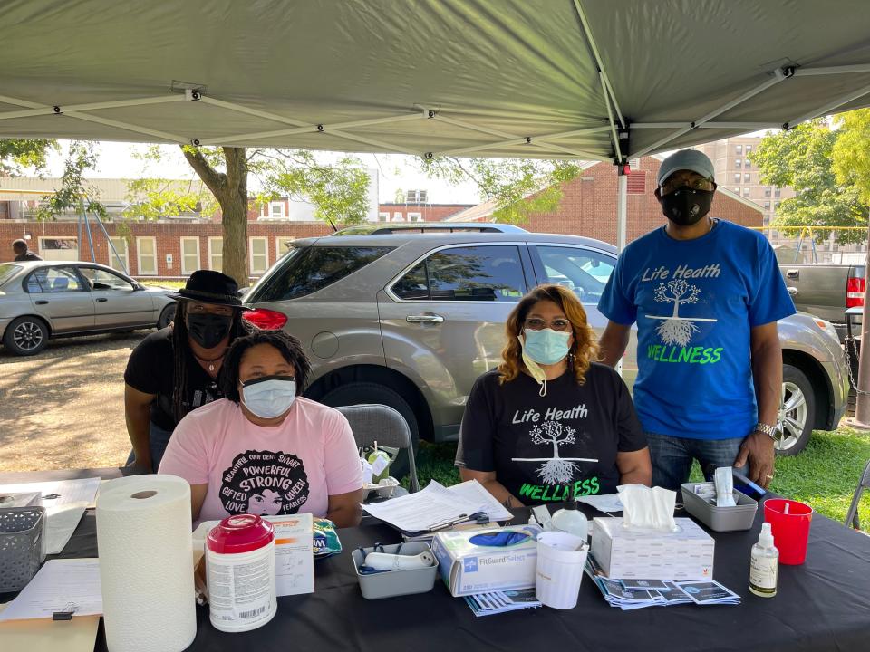 Nurse Kyme McCleary, seated right, and Forrest Watson, standing right, at a mobile vaccination unit, urged people to get tested and receive their COVID-19 shots.