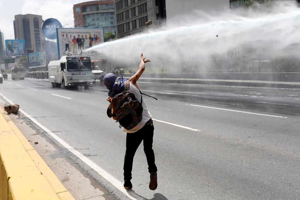 <p>A demonstrator throws a stone toward a water cannon vehicle during a rally against Venezuela’s President Nicolas Maduro in Caracas, Venezuela, May 26, 2017. (Marco Bello/Reuters) </p>