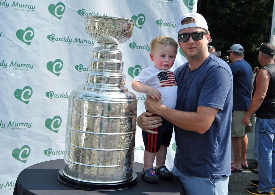 Patrick Sweeney Jr., 2, left, joins his dad, Patrick Sweeney, of Milton, as they check out the Stanley Cup during the launching of the Cassidy Murray Foundation in Milton, Thursday, July 13, 2023.