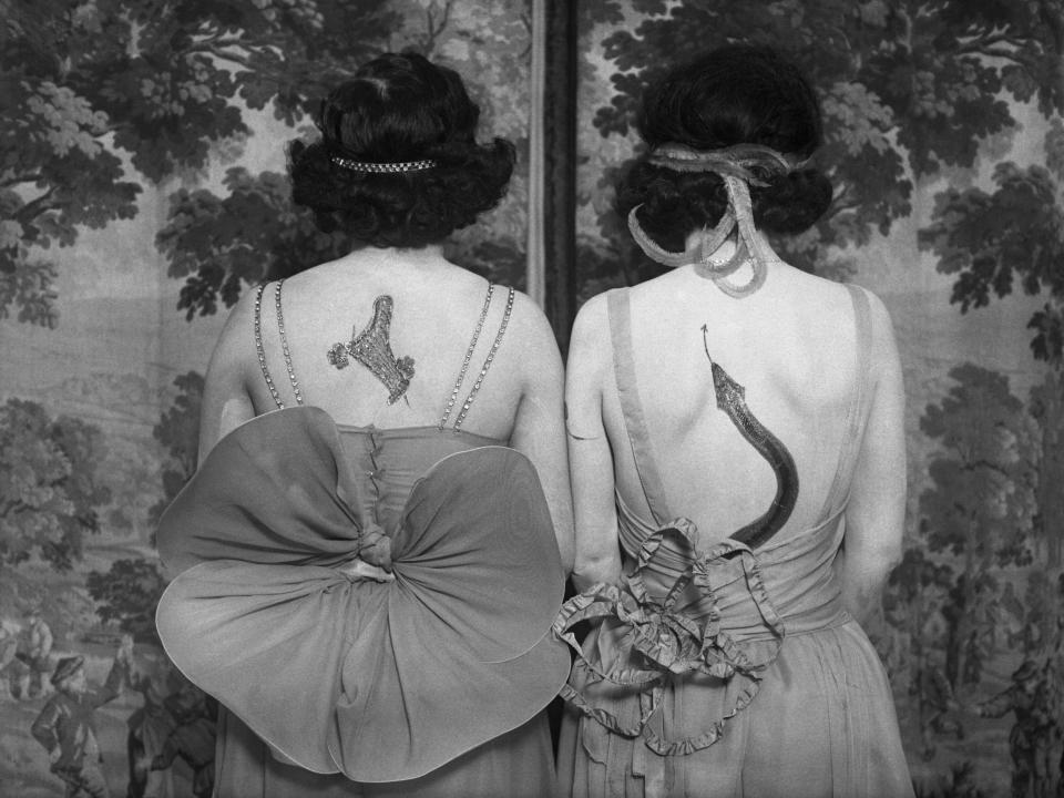 Two women displaying their back tattoos in 1925.