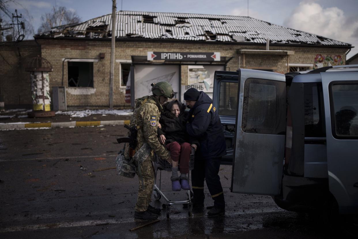 A Ukrainian soldier helps an elderly woman who was being evacuated on a shopping cart from Irpin, in the outskirts of Kyiv, Ukraine, Tuesday, March 8, 2022.