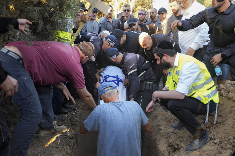 Mourners lower the body of Chen Amir into a grave, during his funeral in Kibbutz Re'im, Israel, Sunday, Aug 6, 2023. On Saturday a Palestinian gunman shot and killed Amir, 42, an Israeli security guard in central Tel Aviv. The attacker was shot and killed. (AP Photo/Tsafrir Abayov)