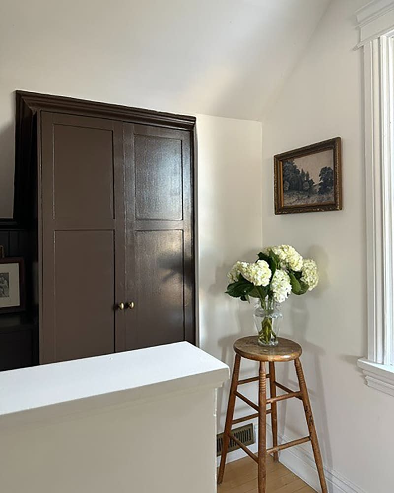 Floral arrangement on stool in hallway.