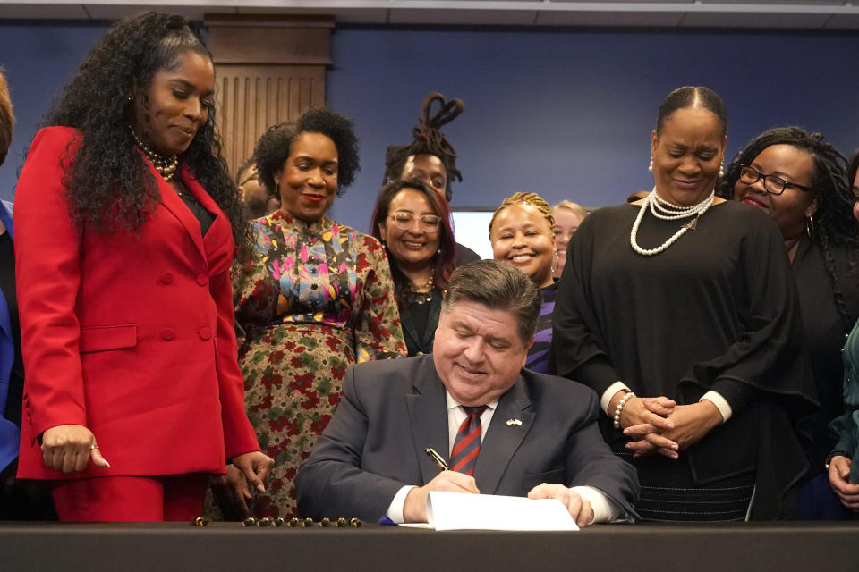 Illinois Gov. J.B. Pritzker signs into law the Paid Leave For All Workers Act as Illinois House Speaker pro-tem Jehan Gordon Booth, left, Lt. Gov. Juliana Stratton, second from left, and Senate Majority Leader Kimberly Lightford, right, watch on Monday, March 13, 2023, in Chicago. Illinois became one of three U.S. states to require employers to offer paid time off for any reason starting in January of 2024. (AP Photo/Charles Rex Arbogast)