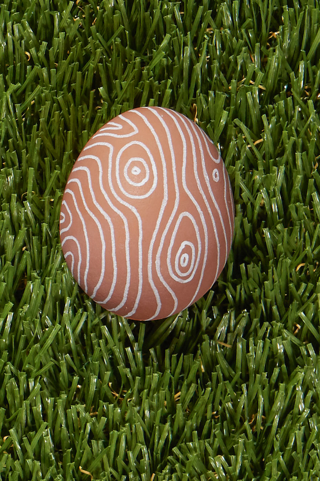 <p><em>Faux bois</em>, meaning false wood, refers to practice of imitating the look of wood grain on any other form of media. Use a white paint pen to draw irregular lines and concentric circles on your egg to get the look. (And hey, even if it’s not convincing as<em> faux bois</em>, you’ll probably still get a cool graphic design.)</p>