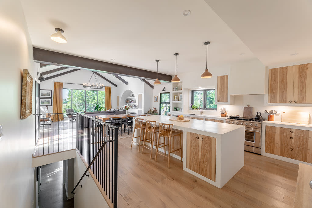  A modern open plan kitchen with wooden floors and white countertops. 