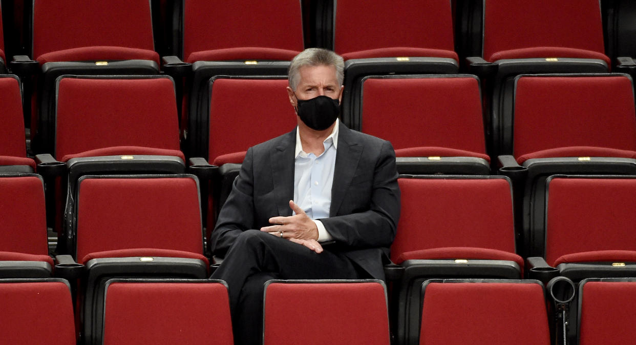 Neil Olshey sits in a row of empty seats wearing a black face mask.