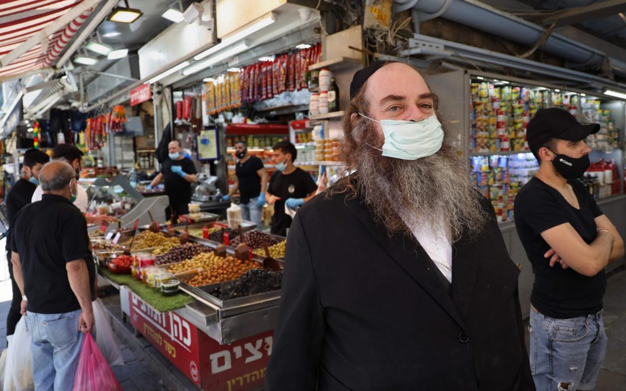 An ultra-Orthodox Jewish man wears a protective face mask as he shops at Jerusalem's Mahane Yehuda market, on May 8, 2020. - Markets and shopping malls have reopened across Israel after temporarily being closed for more than a month in order to prevent the spread of coronavirus - MENAHEM KAHANA/AFP