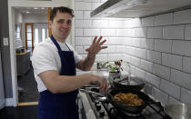 Jon Watts, demonstrates his cooking skills for the Associated Press by making a prawn linguini at a friends kitchen in Codicote, Welwyn, England, Thursday, April 15, 2021. Jon Watts was 18 years old when he woke up in a prison cell and decided he had to change. He enrolled in every course he could find, from mathematics to business. But he says it was a program founded by Prince Philip, the Duke of Edinburgh, that gave him a “passion for food” and a career as a chef when he got out of prison 3 1/2 years later. (AP Photo/Alastair Grant)