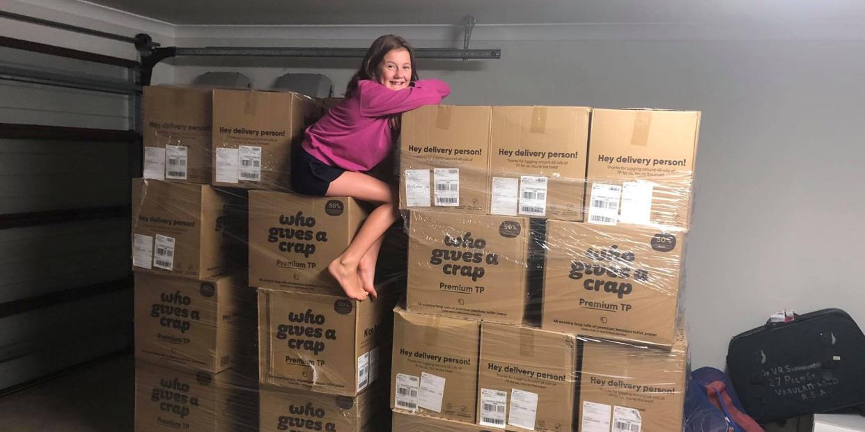 A girl sits on top of boxes containing toilet paper in Toowoomba, Australia.