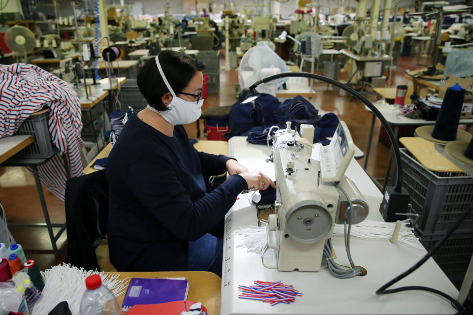 In this Friday, June 12, 2020 photo, an employee sews face protective masks in Chanteclair Hosiery, a French knitwear clothing manufacturer in Saint Pouange, east of Paris. The French praised the altruism of luxury goods companies such as LVMH, Kering and Chanel, for altruism for diverting their production facilities to make millions of face masks for the public during the peak of their country's coronavirus outbreak. Now, the companies that helped France avoid a dangerous shortage say they need help unloading a surplus of 20 million washable masks. (AP Photo/Francois Mori)