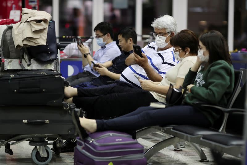 Travellers, wearing masks as a precautionary measure to avoid contracting coronavirus, are seen at Guarulhos International Airport in Guarulhos