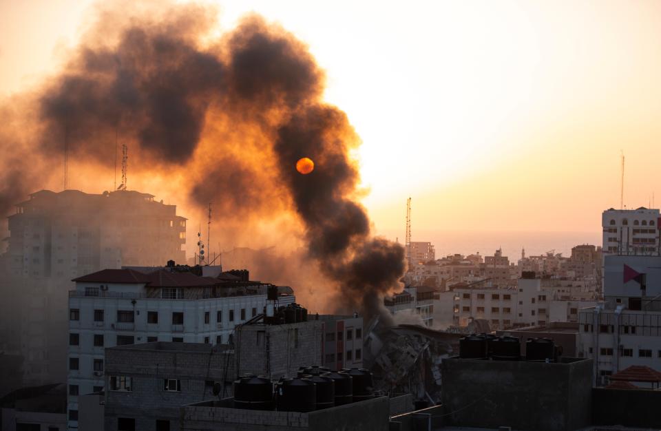 <p>Smoke rises from a collapsed building hit by Israeli air strikes on Gaza City</p> (AP)