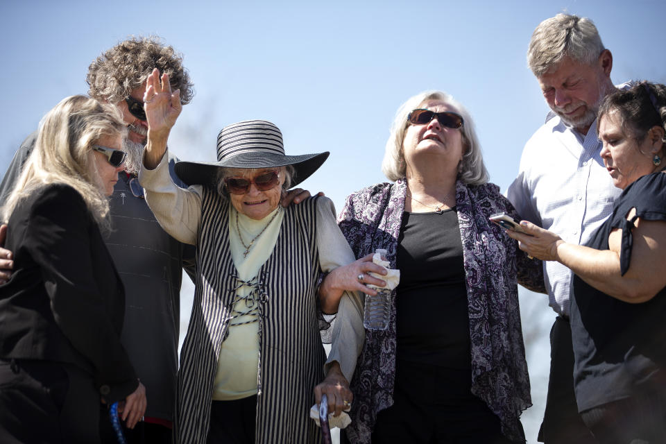 Debbie Brooks, from left, Christopher Casasanta, Donna Casasanta, Cheryl Clouse, Les Linn and Tess Welch embrace and pray at the gravesite of their loved ones, Harold Dean Clouse and his wife, Tina Gail Linn, in the Harris County Cemetery #2, Tuesday, March 1, 2022, in Houston. Their bodies were discovered in a wooded patch of land in northeast Harris County in January, 1981, but not identified until late last year. (Brett Coomer/Houston Chronicle via AP)