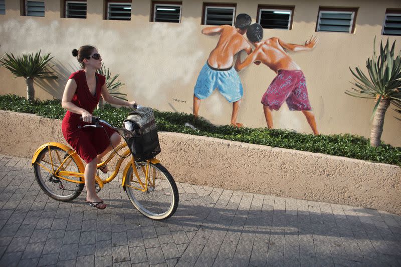 FILE PHOTO: A woman cycles next to changing rooms as she leaves the beach in Tel Aviv